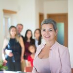 Confident female realtor in office with family background, showcasing professionalism and success.